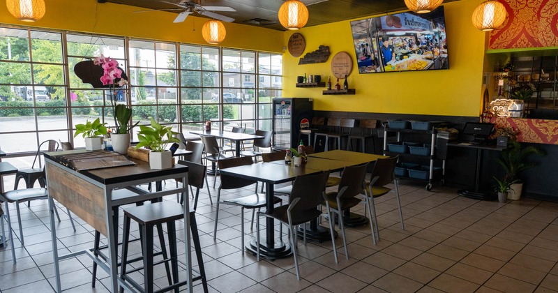 Interior, yellow walls, wooden tables and chairs, hanging wicker lights, and a large window view