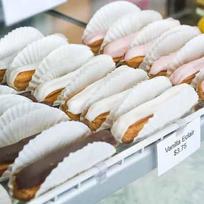 Vanilla eclairs displayed in a glass case.