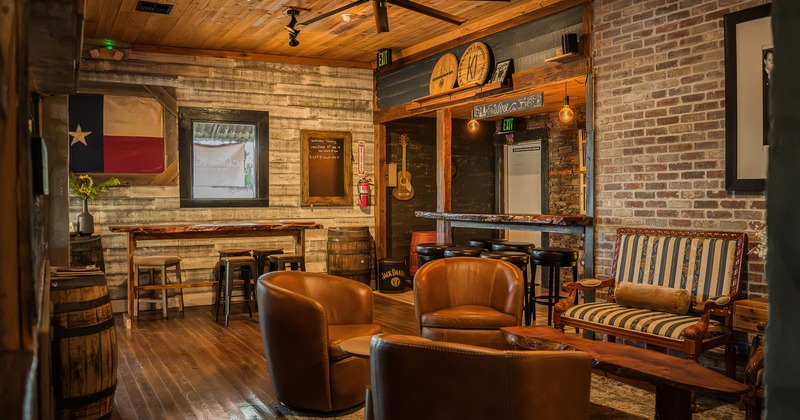 A warm and rustic design of interior seating area with leather lounge chairs and a cozy bar area