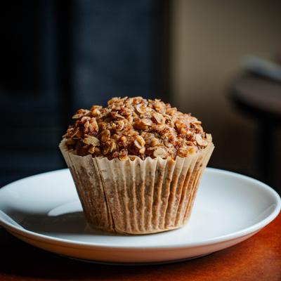 Oatmeal muffin featuring a crunchy top and a paper liner.
