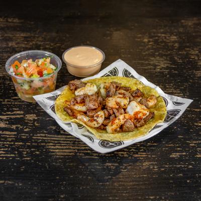 Chicken, steak, and shrimp taco, with a side salad and sauce.