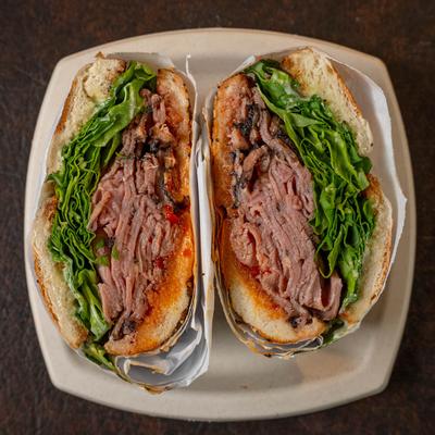 The Roasted Cow sandwich on a beige plate atop a dark table.