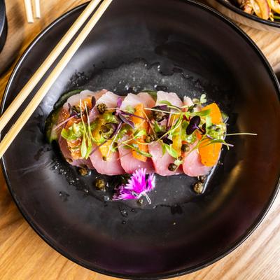 Hamachi carpaccio with citrus and herb topping.