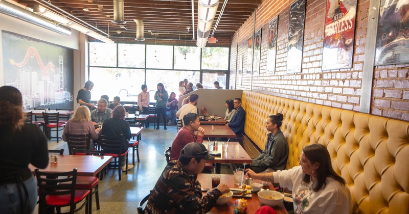 Interior, tables, chairs and buttoned yellow leather bench, guests enjoying their food