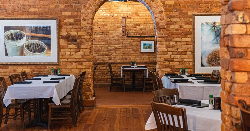 Interior, tables and seats ready for guests, brick walls decorated with pictures