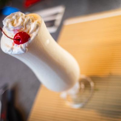 Pina Colada topped with whipped cream and garnished with a cherry.