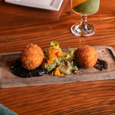 Fried goat cheese poppers with charred citrus, burnt honey, and squid ink aioli.
