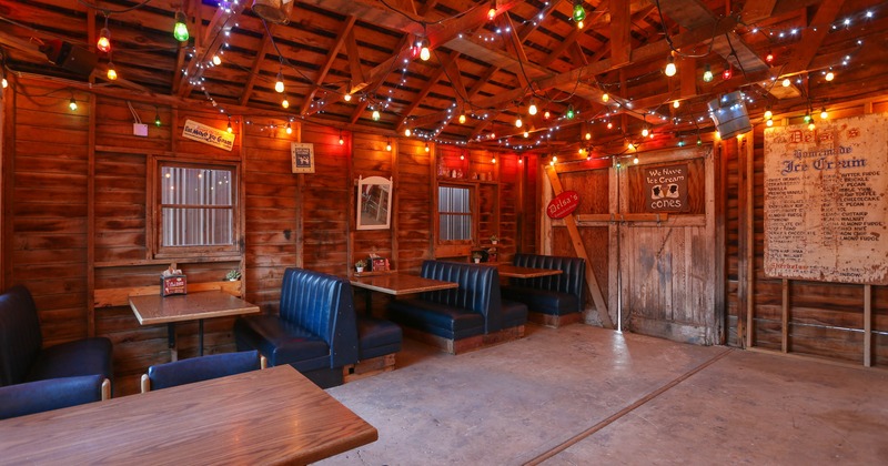 Interior dining area with wooden walls, string lights and blue booths