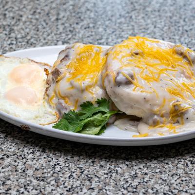 Biscuits and gravy topped with shredded cheese and served with two fried eggs.