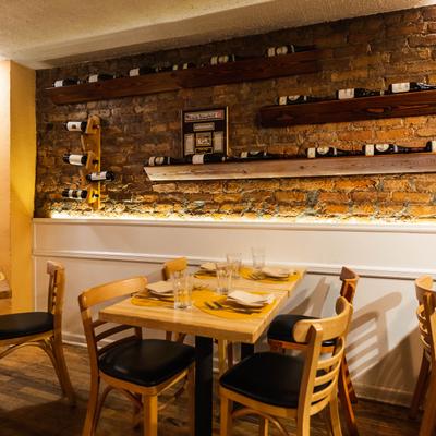 Interior, a table set for dining in  a room with wine shelves on a brick wall.