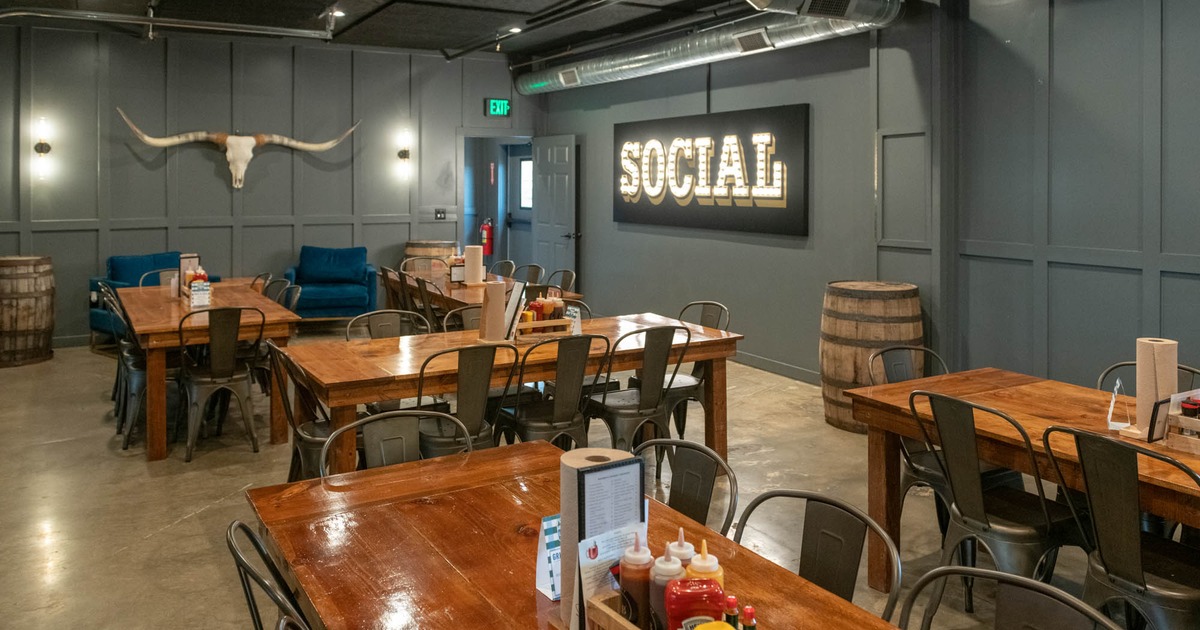 Interior, dining area, wooden top tables for eight, concrete flooring, back entrance