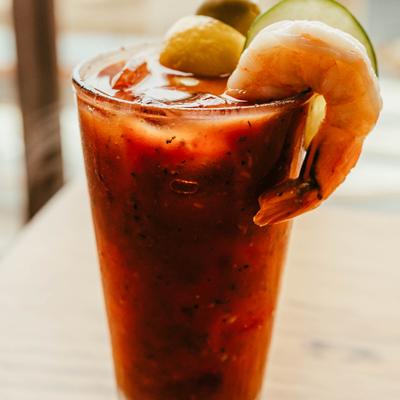 Bloody Mary cocktail garnished with a shrimp, olive, lemon and cocamber slices.