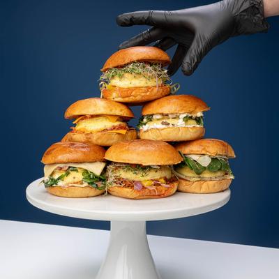 A hand stacking burgers on top of each other.