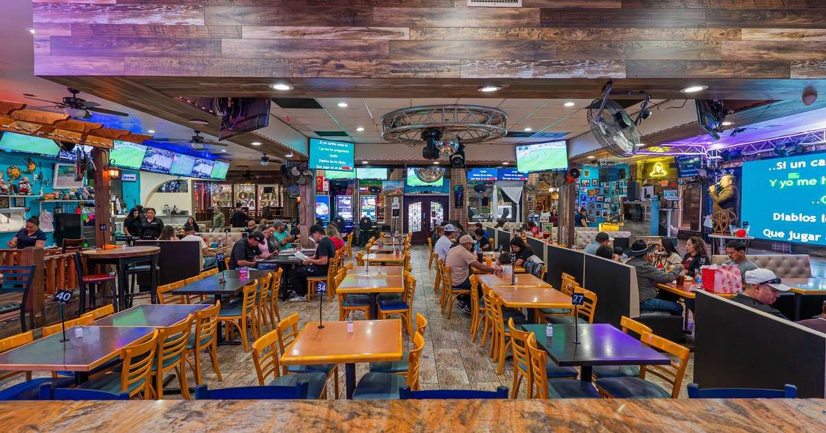 Interior with numerous television screens, rustic ceiling design and mix of seating options