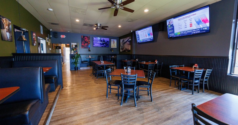 Interior of a restaurant with wooden tables, booth seating, mounted televisions