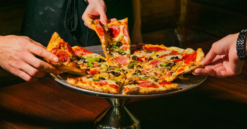 People sharing a Supreme pizza