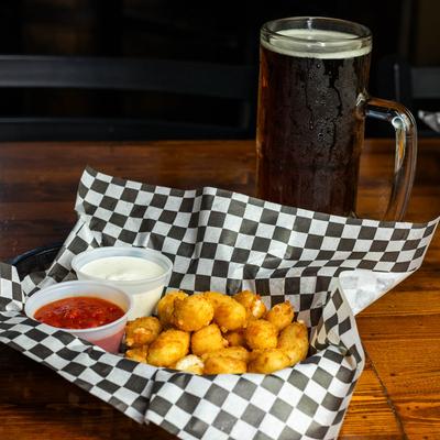 Garlic Cheese Curds served on a table with a pint of beer.