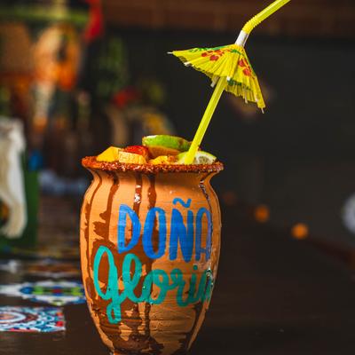 Cantarito cocktail served in a chili-rimmed clay pot with various farnishes.