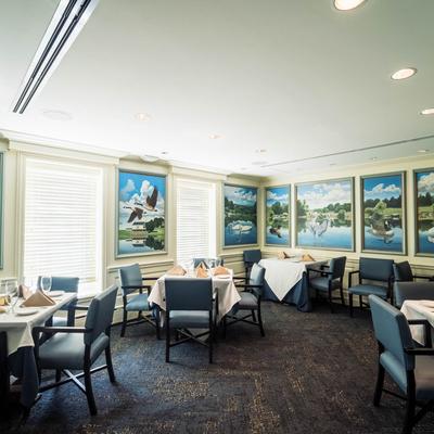 Interior with tables set for guests and waterfowl-themed wall art.
