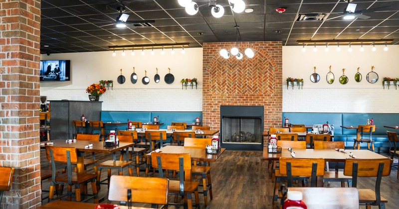 Interior seating area with wooden tables, a brick fireplace and globe lights