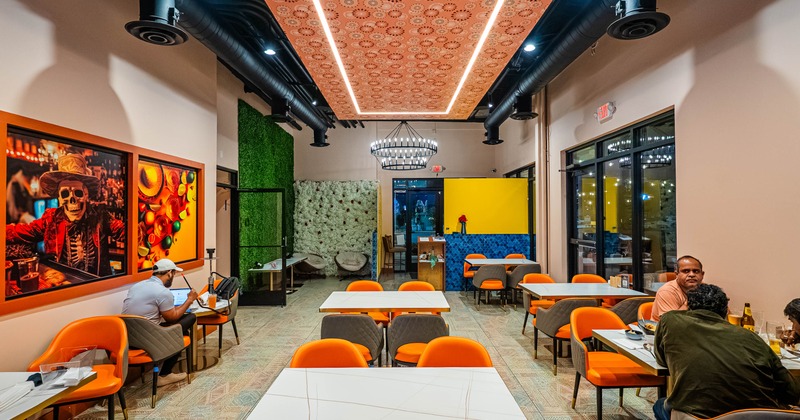 Modern dining area with orange seating and colorful wall art