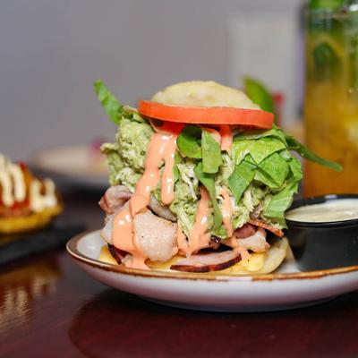 Arepa with BLT, ham, cheese, salad, and pink sauce.