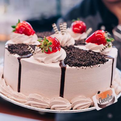 A cake topped with fresh strawberries and drizzled with chocolate sauce.