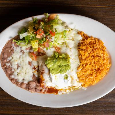 Enchiladas with green and red salsas, sour cream, guacamole, salad, rice, and beans.