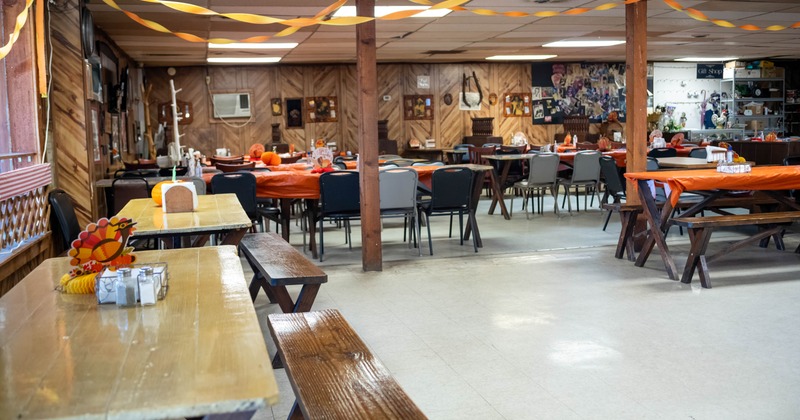 A community hall set up for a festive gathering with tables and chairs, orange tablecloths