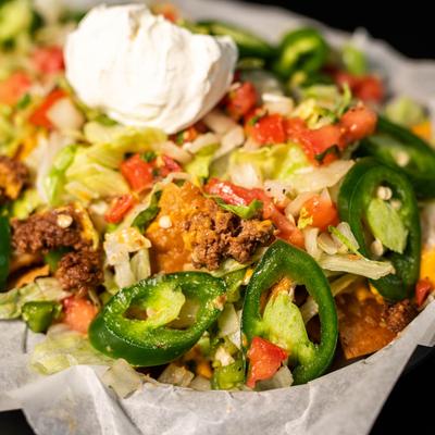 Loaded nachos with ground beer cheese, sour cream, lettuce, jalapenos, pico de gallo, chips.