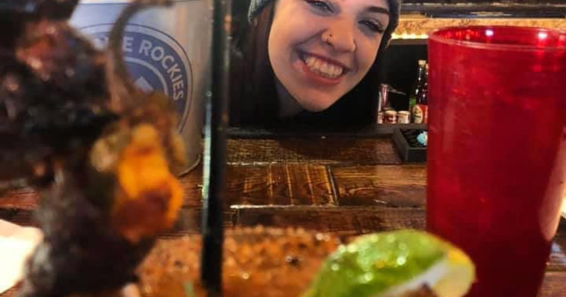 An employee laughing behind glasses of cocktails