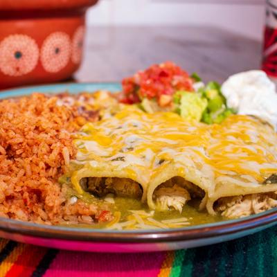 Enchiladas in green sauce, with rice, beans, salsa, guacamole, and sour cream.