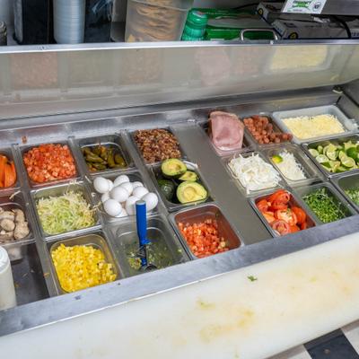 Prep station featuring multiple compartments filled with fresh ingredients.