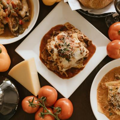 Table setting with Italian dishes, cheese wedge and fresh vegetables.