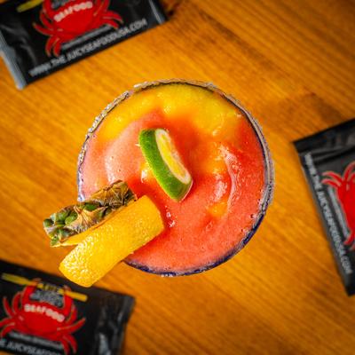 Frozen Margarita topped with a lime slice, pineapple, and orange peel garnish.