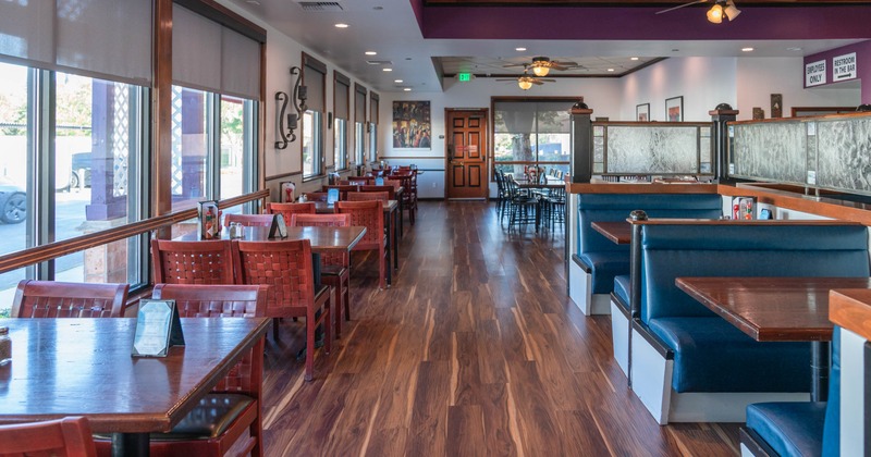 Interior of a restaurant with tables, chairs, booths, and large windows