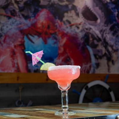 Strawberry margarita with a salted rim, garnished with lime and a paper umbrella.