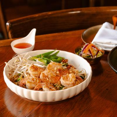 Shrimp Pad Thai served with bean sprouts, green onions, and a side of sauce.