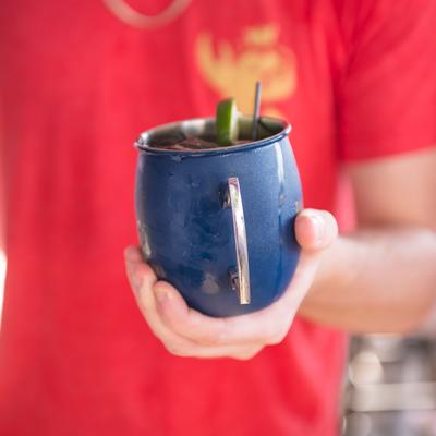 Closeup of a person's hand holding Moscow Mule cocktail drink.