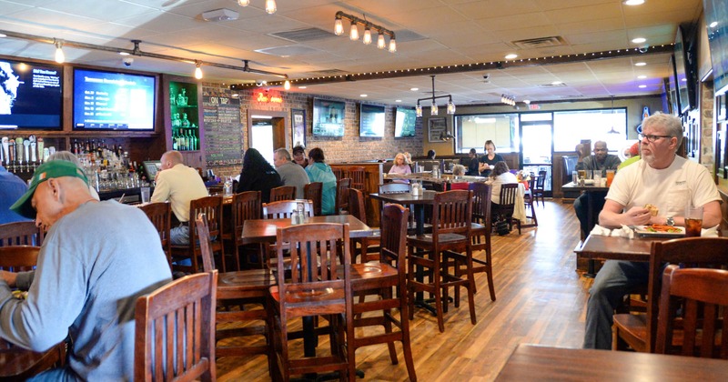 Interior, tables, chairs, many customers sitting, LED TVs and menus, windows, glass doors