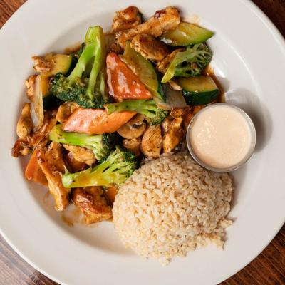 Chicken stir-fry with vegetables, rice, and dipping sauce.