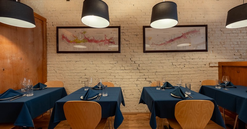 Interior with blue tablecloths, white brick walls, and black pendant lights