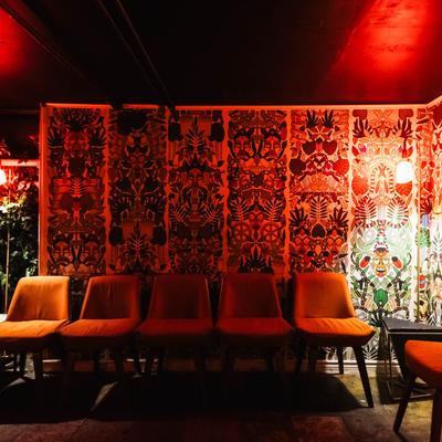 Interior, seats by a wall with flower pattern wallpaper.