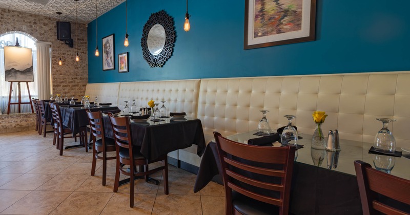 Interior - blue accent wall, tufted seating and tables set with black tablecloths and glassware
