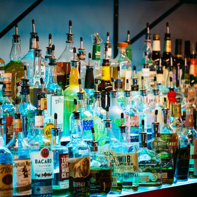 A well-stocked bar shelf displaying an extensive collection of liquor bottles in various shapes and colors.