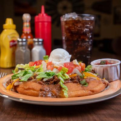 Indian Taco, with ground beef, lettuce, onion, lettuce, cheese, and sour cream.
