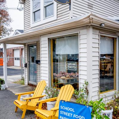Side view at the entrance with a sign and two yellow chairs in front of it.