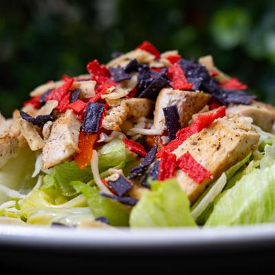 Santa Fe Chicken Salad topped with crunchy red and blue tortilla strips, close-up.