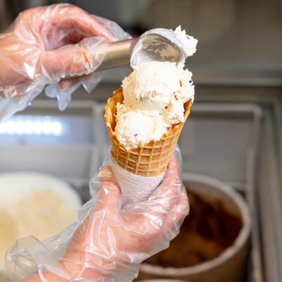 An employee fills a cone with ice cream.