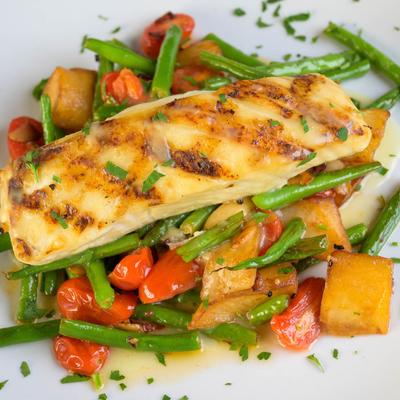 Grilled fish fillet atop a vegetable medley.